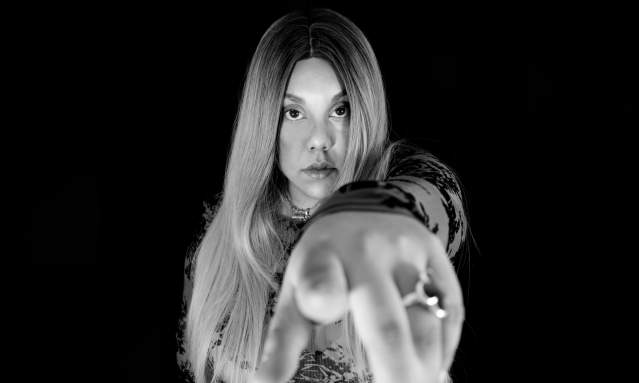 Black and white photo of a woman pointing at the camera.