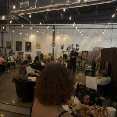 Guests enjoying a poetry reading at a local venue in Fayetteville, NC, with string lights and artwork on display.