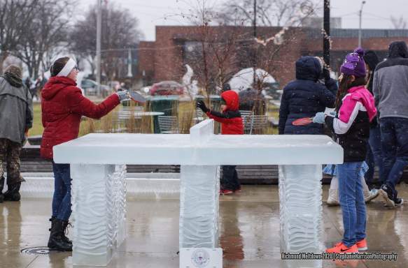 Two kids playing ping pong on a table carved of ice at Freezefest