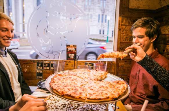 A slice of cheese pizza being served at a table at Mother Bear's Pizza