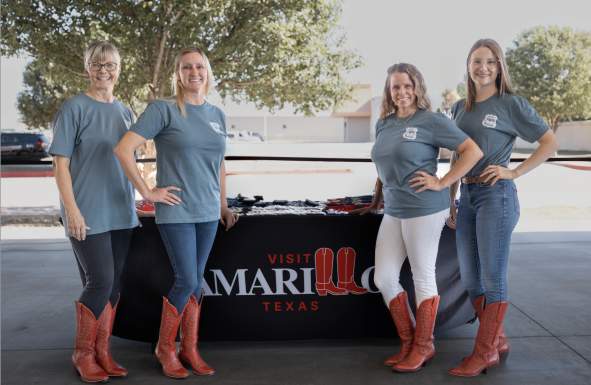 Women posing in front of visit amarillo booth