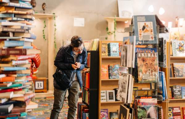 Person in a winter coat shopping for books at Midnight Oil Bookstore