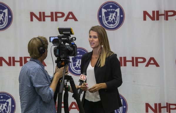 A camera person interviews Meghan Ziehmer, Executive Director of the Greater Lansing Sports Authority.