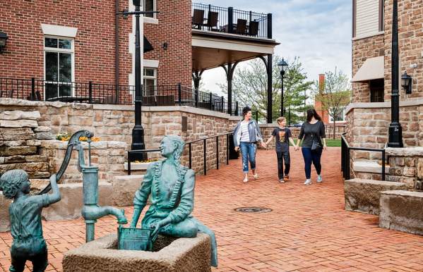 Two older women and a young boy holds hands and walk towards the public art piece, Daily Chores, in Historic Dublin.