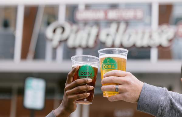 Two DORA cups cheersing in front of Urban's Pint House