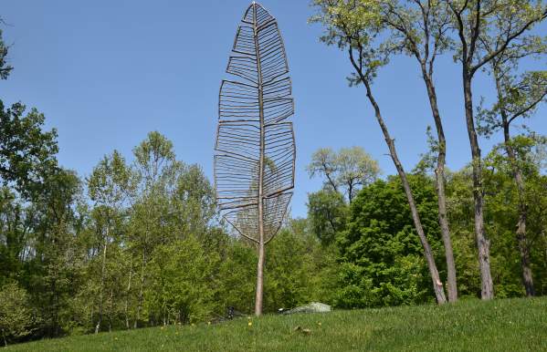 A 20-foot giant feather sculpture in a park.