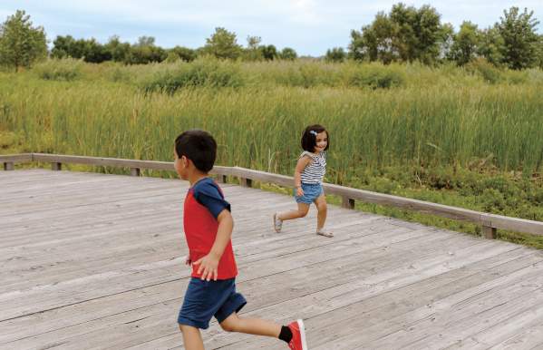 Two kids running around each other on the boardwalk at Glacier Ridge Metro Park