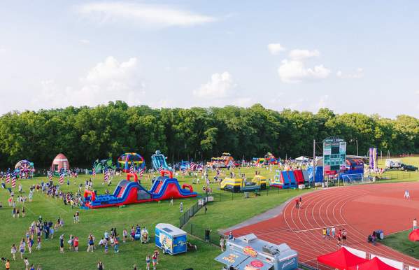 A crowd enjoys the Independence Day Kids Zone in Dublin, Ohio, filled with inflatable slides, obstacle courses, and food trucks.