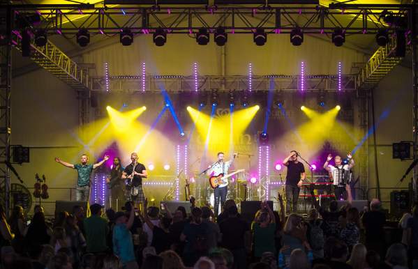 Band performing to a crowd on stage under bright yellow lights on the Celtic Rock Stage at the Dublin Irish Festival