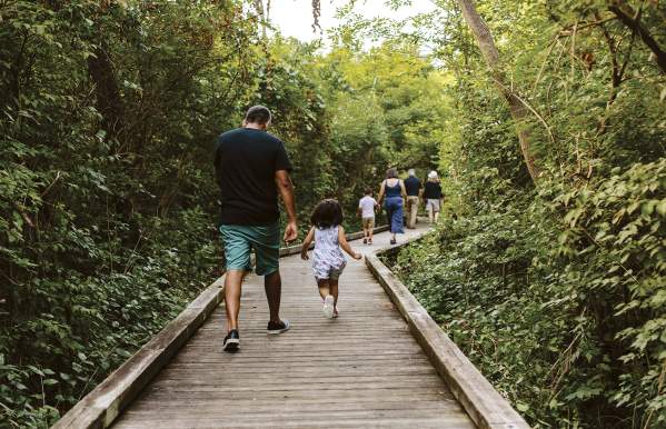 A family running down the boardwalk at Kiwanis Riverway Park