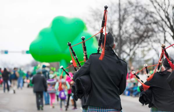 St. Patrick's Day Parade Bagpiper walking behind a giant green shamrock balloon.