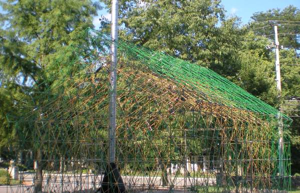 Public art installation that looks like a house made out of green and yellow wires