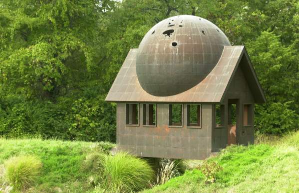 A small bronze house with doors and windows and a globe on the roof.