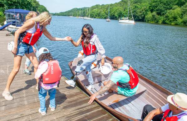 rowing boat visitor with prosthetic leg is helped out of boat