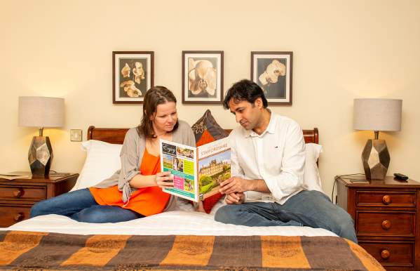 couple sit on bed reading guide book