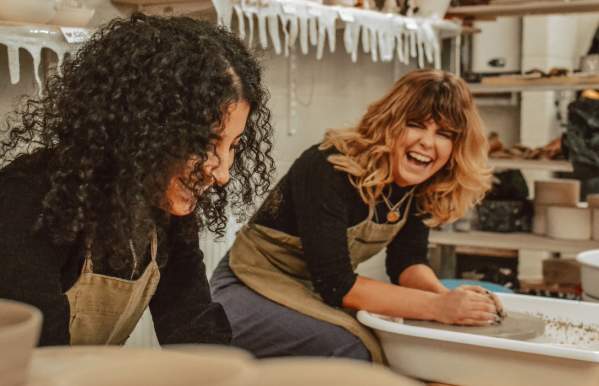 two friends laughing in a pottery class