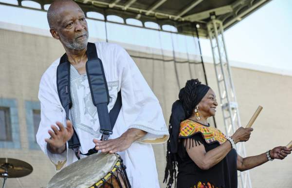 man playing a hand drum, woman shaking a sticks