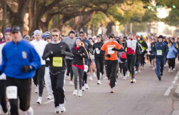 group of people running down the street in a race