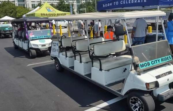 Two white eight-seater golf carts in front of a blue tent