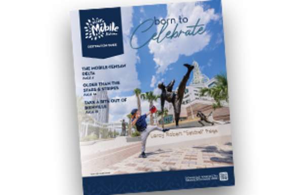 Cover of the 2026 Destination Guide - a boy posing like he is throwing a baseball in front of a statue of Satchel Paige