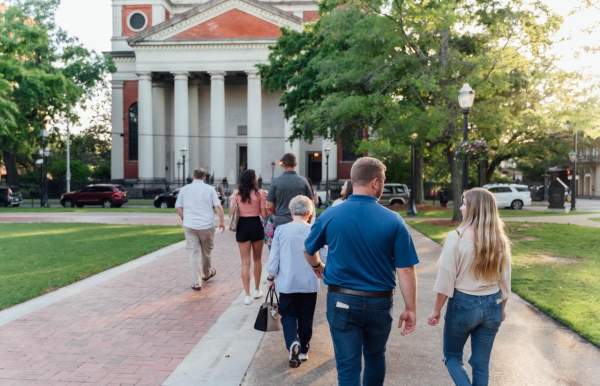 Men and women walk together on a sidewalk towards a large church