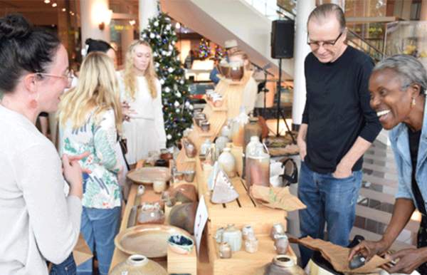 Men and women shop at tables of crafts and holiday decorations