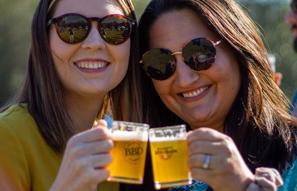 Two women making a toast with mugs of beer