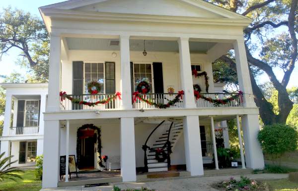 white two-story building with four columns and Christmas wreaths and garland