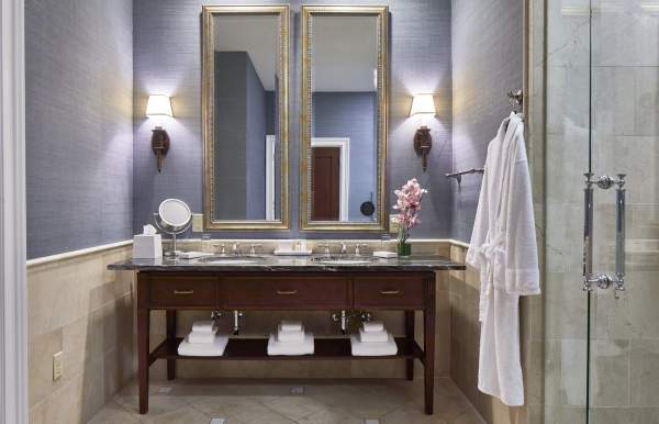 Hotel bathroom with double mirror over sink and robe hanging on the wall next to shower door