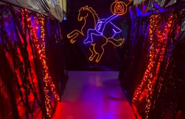 Purple and orange lights on black drapery with a lighted outline of the headless horseman in purple and orange lights