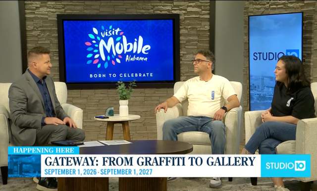 A male television news anchor sits beside a man and a woman who he is interviewing