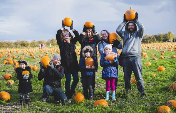 family with their pumpkin haul in the patch