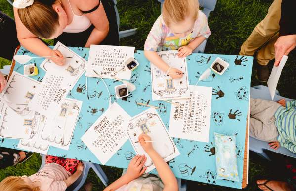 five people trying medieval writing at a table