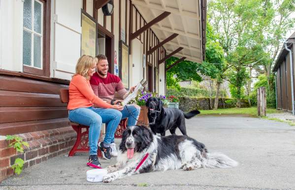 couple sit on bench by Manifold Visitor Centre reading leaflet