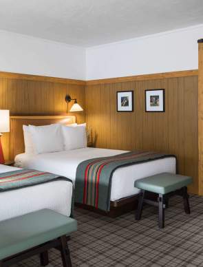 Hotel room with two made beds and open doorway to en suite bathroom.