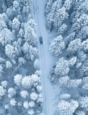 Aerial view of car driving downm a snowy road in Wyoming winter.