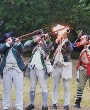 A group of historical Revolutionary War reenactors firing away at a Revolutionary War demonstration on Long Island.