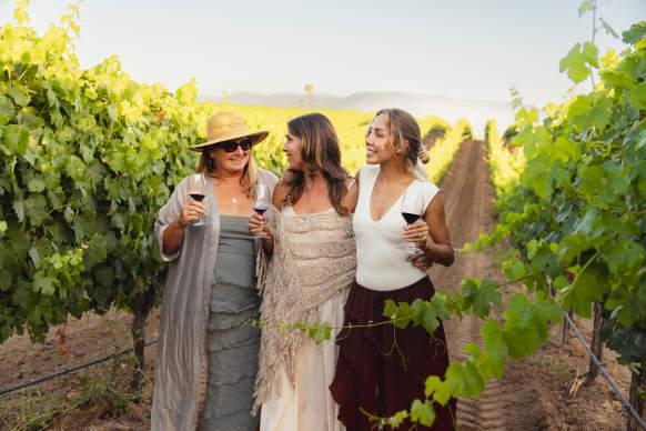 Three woman walking through the vineyards enjoying wine