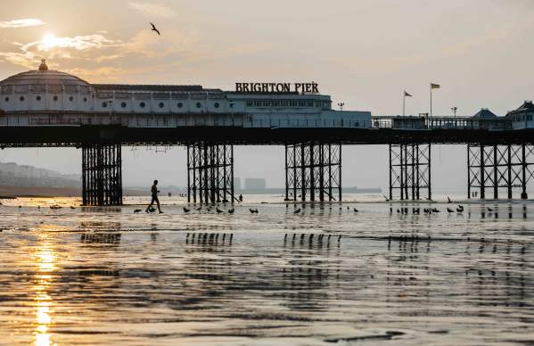 Brighton pier at low tide with the sun rising in the background