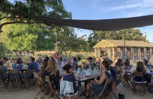 People eating at a Farm to Table Dinner, watching a speaker in the background.