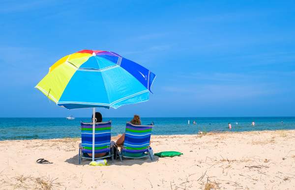Beach Umbrella with People in Beach Chairs
