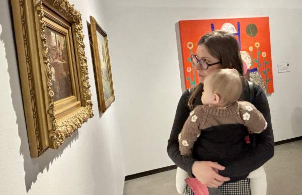 Woman holding baby looks at painting at Muskegon Museum of Art