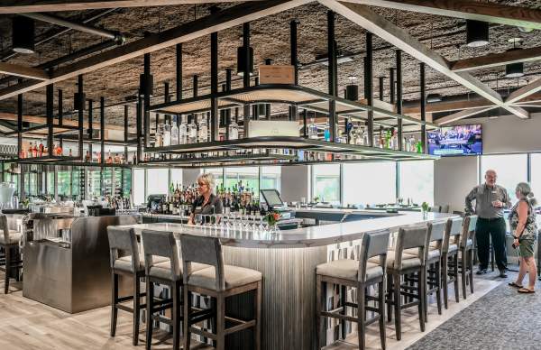 bar with bar stools around, glass wear hanging above bar