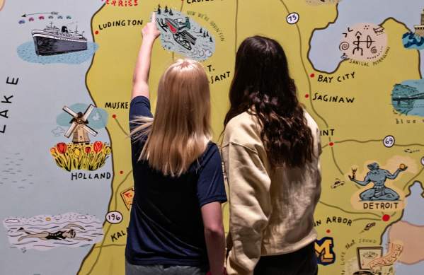 Two girls looking at mural of michigan map