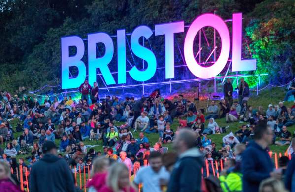 People sitting around a luminous Bristol sign at Bristol International Balloon Fiesta - credit Paul Box