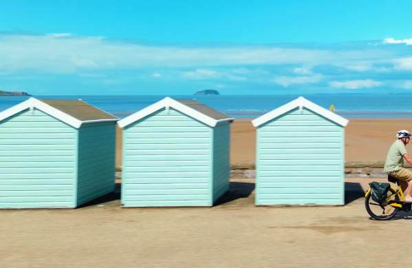 Cycling past beach huts in Weston-super-Mare - credit Siddiqui Media