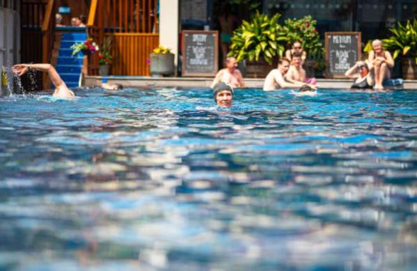 A lady wearing a grey swimming cap swimming at Bristol Lido