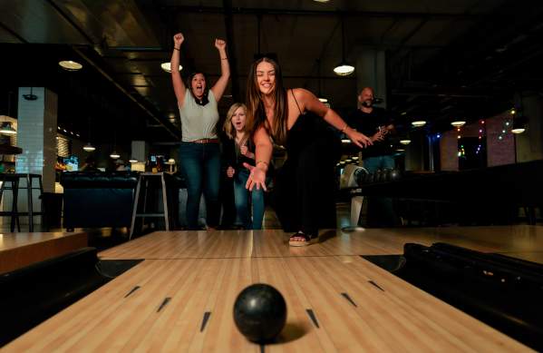 A group of friends celebrating on a duckpin bowling lane at PINS Mechanical