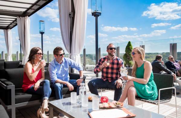 Two couples enjoying cocktails on the rooftop patio at VASO