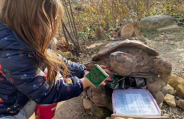 Little girl discovering a Riverbox shaped like a turtle and stamping her passport